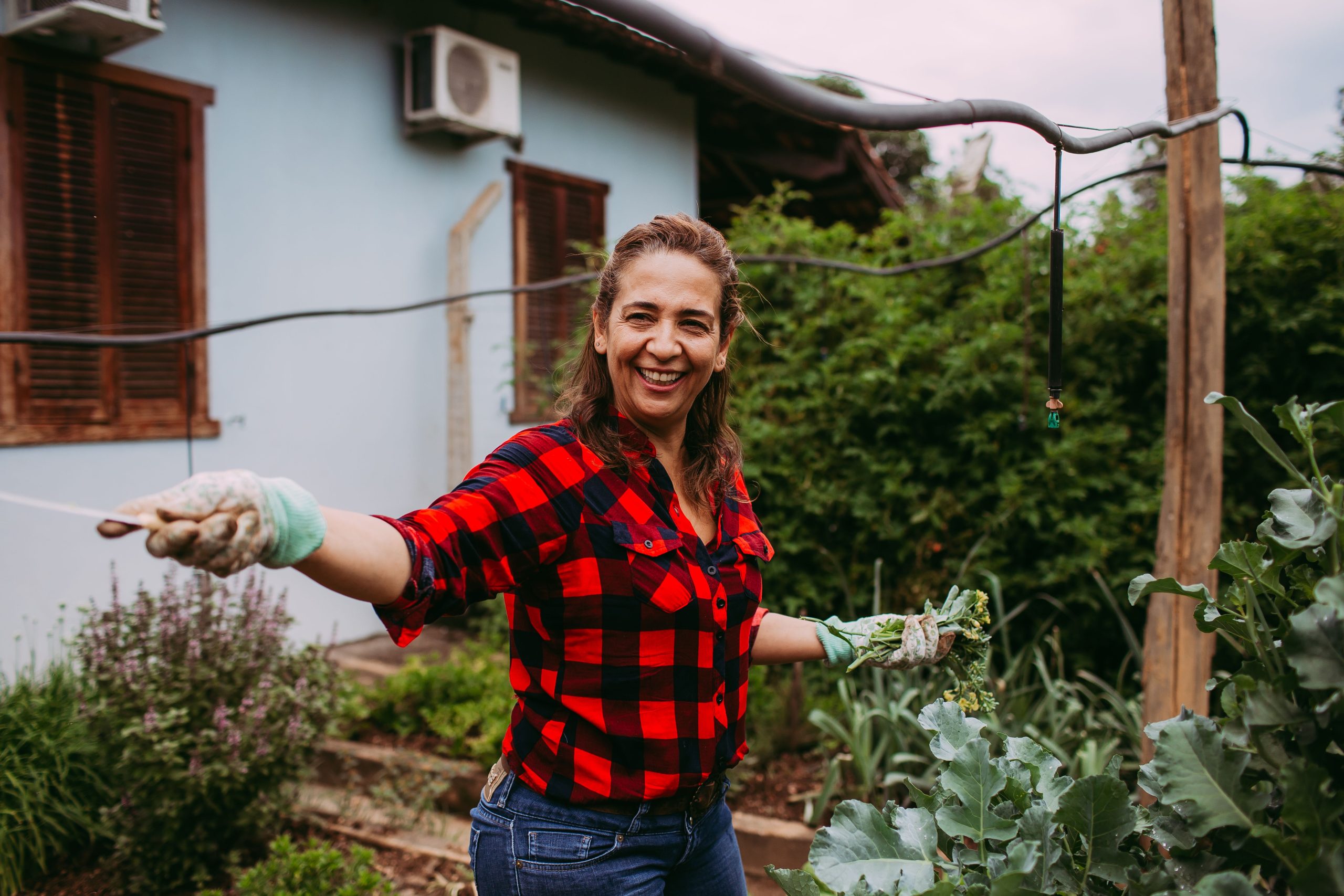 Femme souriante cultivant son jardin écologique