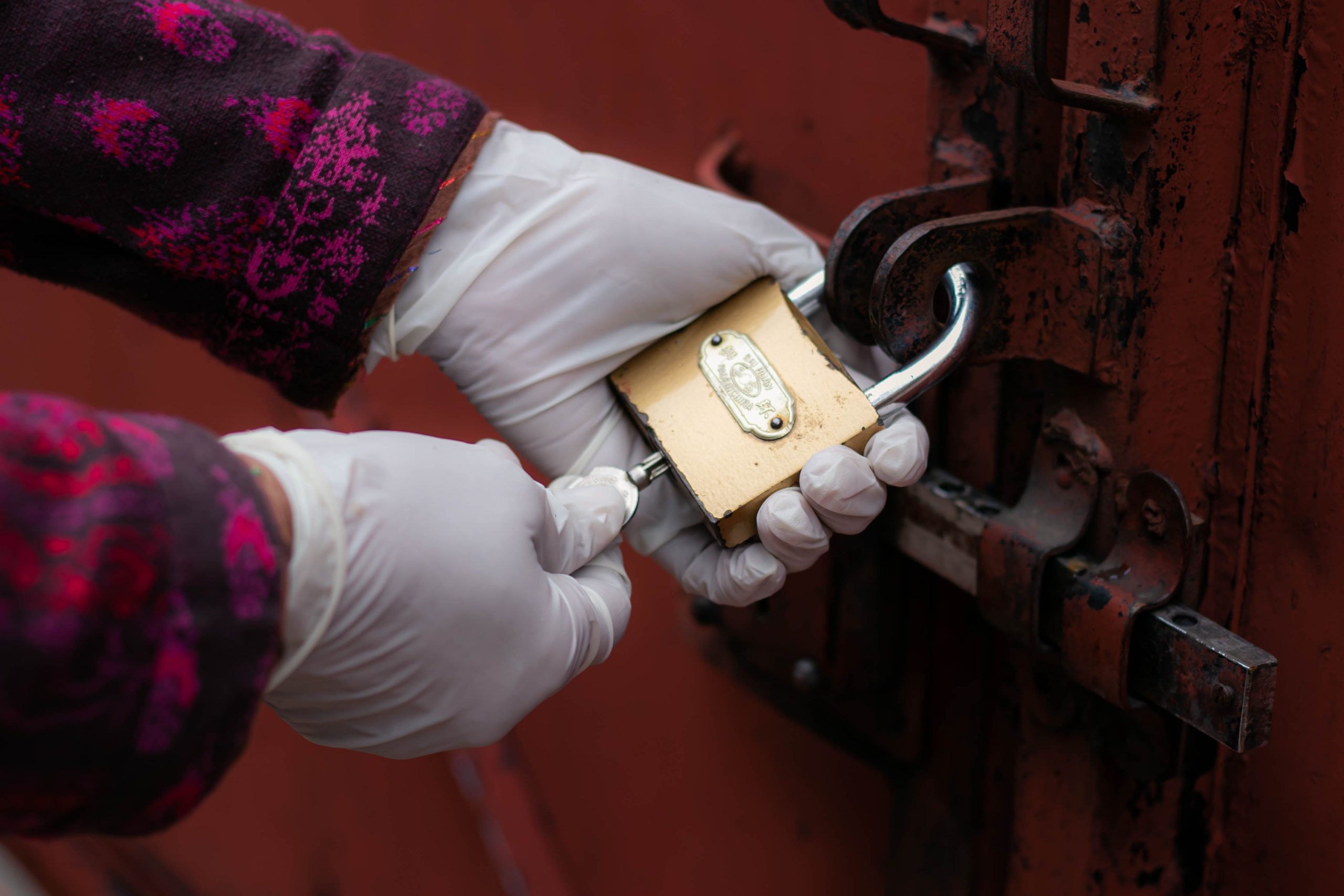 Mains gantées déverrouillant cadenas porte rouille