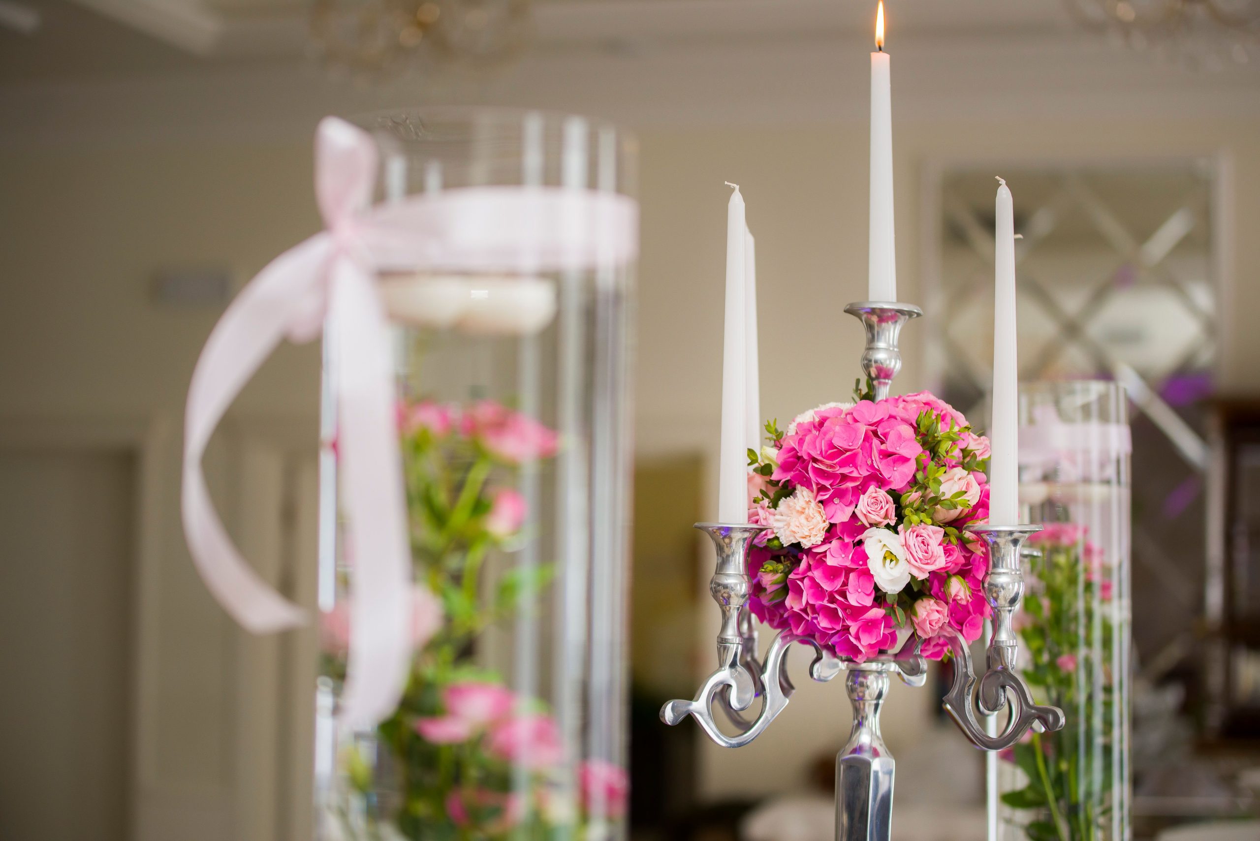 Chandelier blanc avec fleurs delicates et vases remplis fleurs.