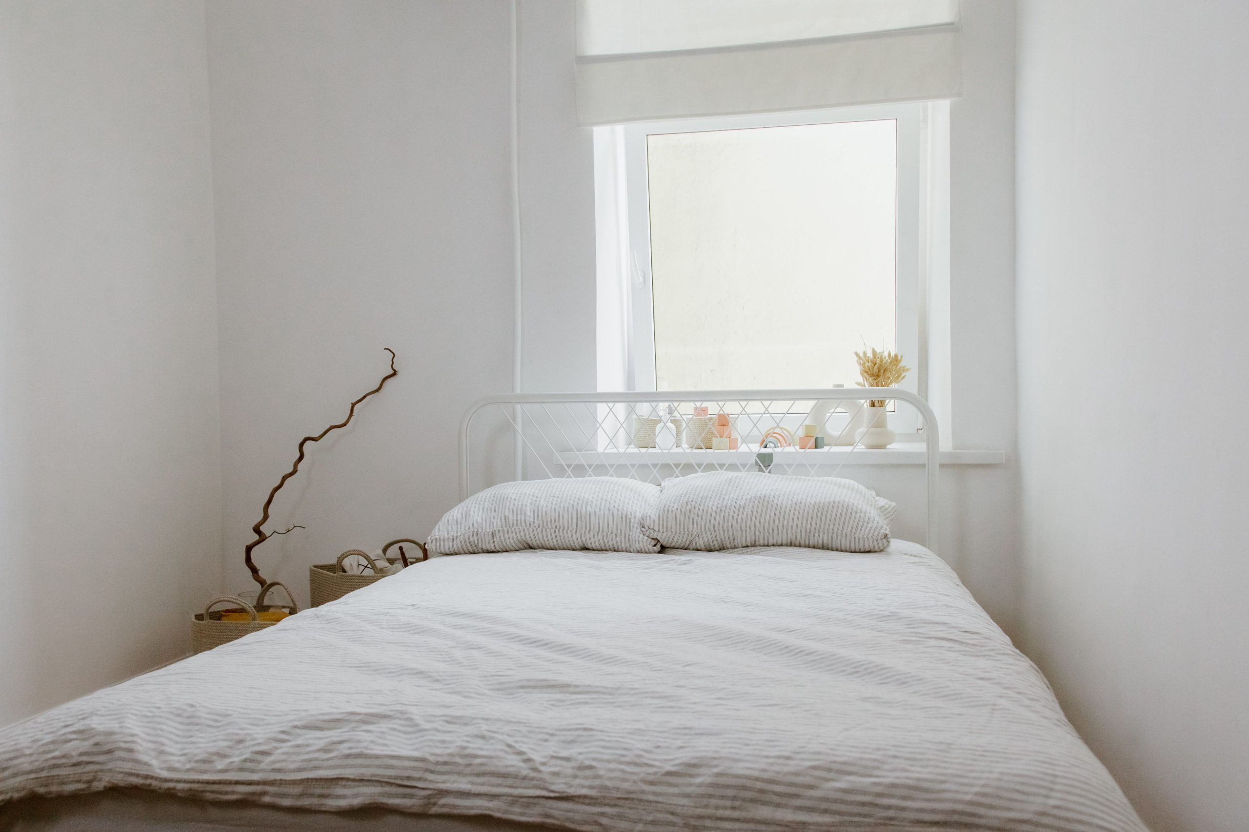 Chambre blanche sereine avec lit et lumière naturelle