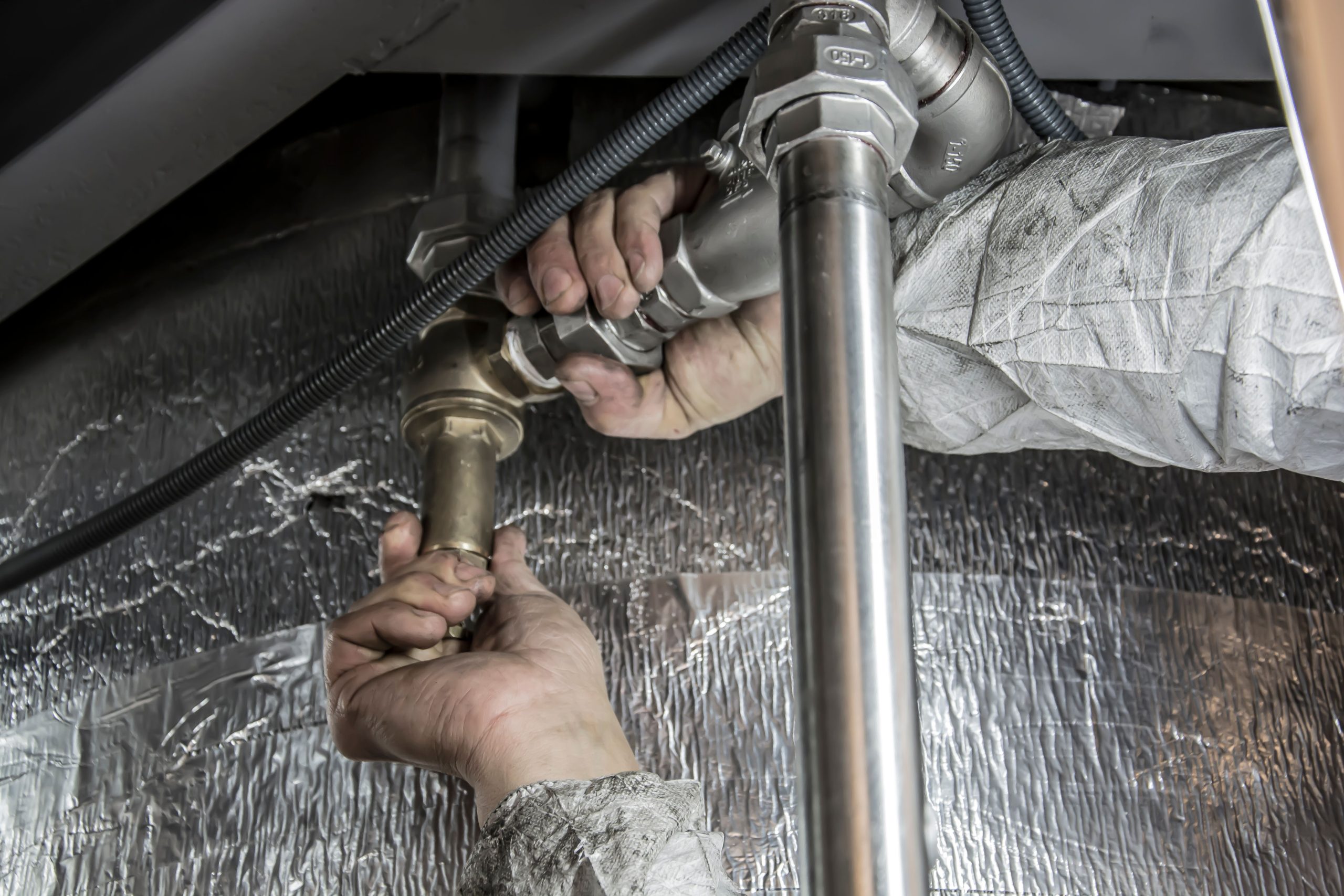 Mains plombier installant tuyauterie acier chauffage
